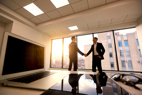 Two Business men shaking hands near a window